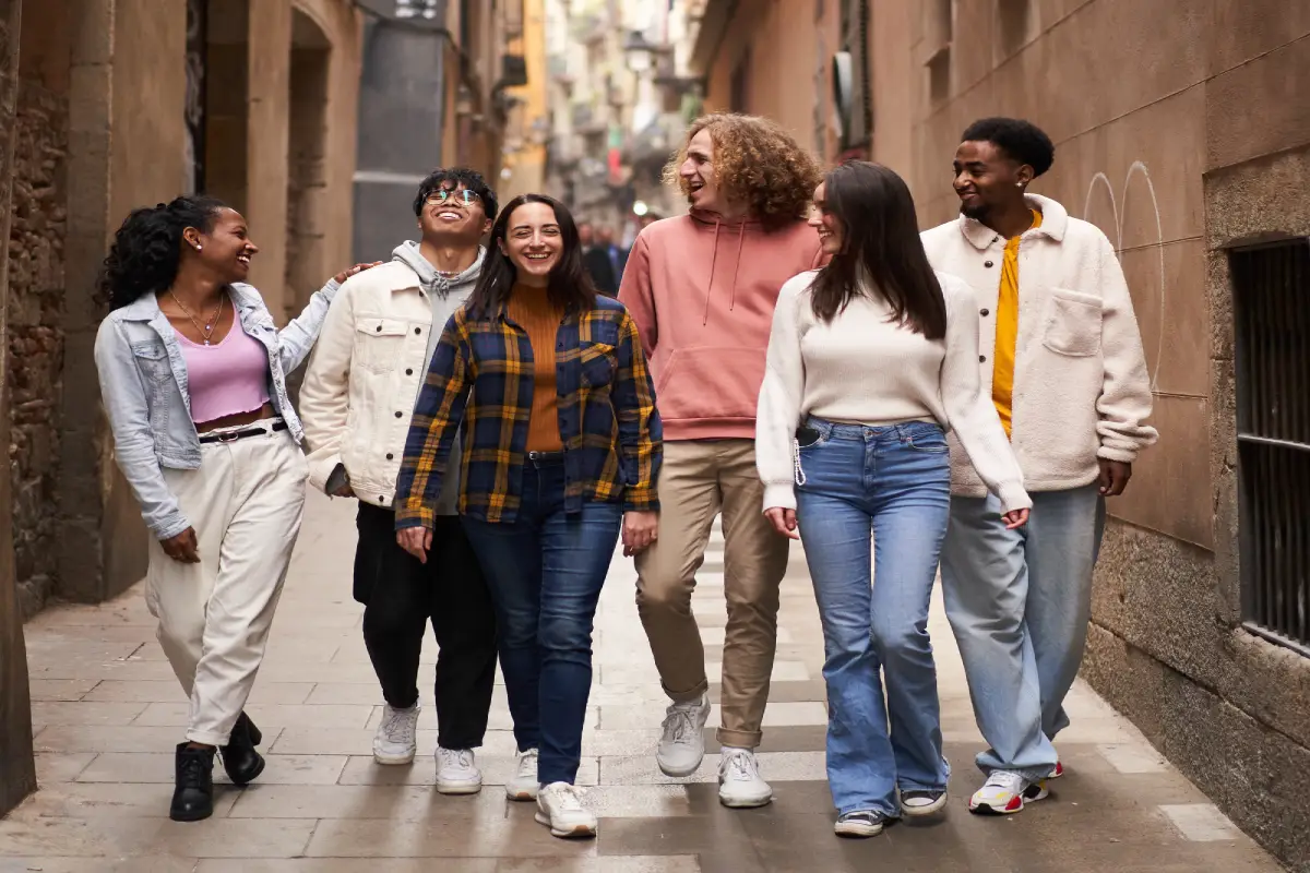 Grupo diverso de amigos caminando alegremente por una calle estrecha y tradicional de Granada, disfrutando de un paseo por la ciudad